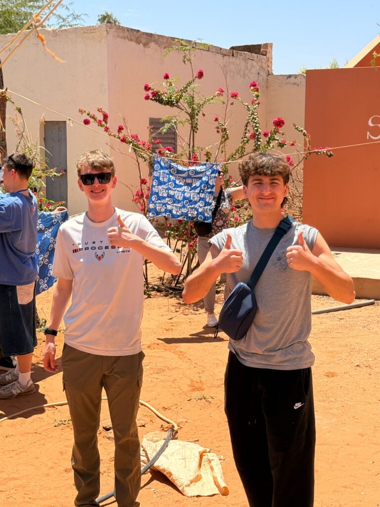 Students displaying handmade batik artwork during a student trip to Senegal