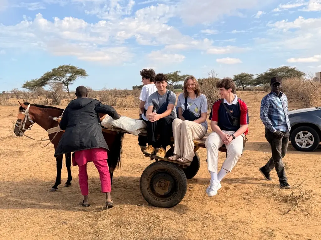 Students riding a donkey cart during a cultural experience in rural Senegal